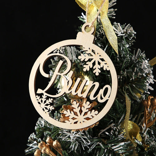 Bola de Navidad de madera con un nombre recortado, colgada en el árbol