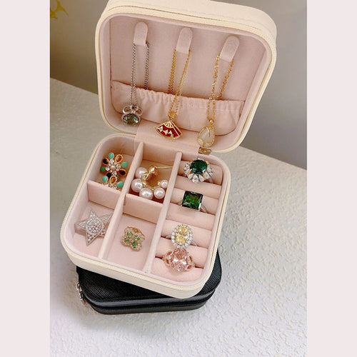 Caja de joyas blanca abierta, con collares y anillos