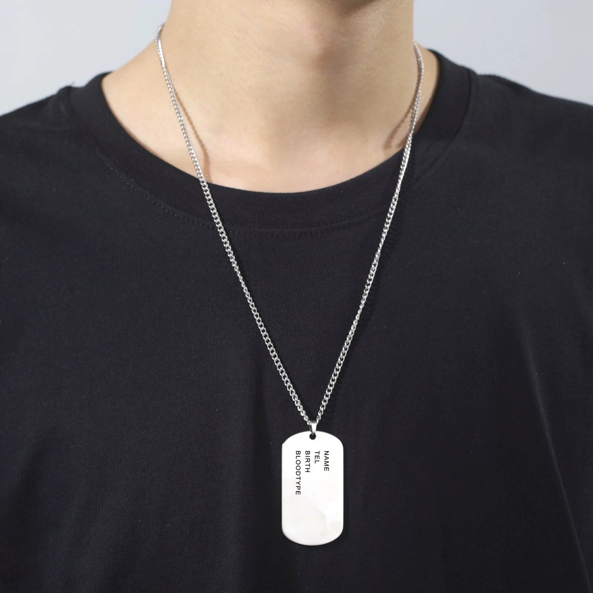 Colar com chapa ao pescoço, sobre t-shirt preta