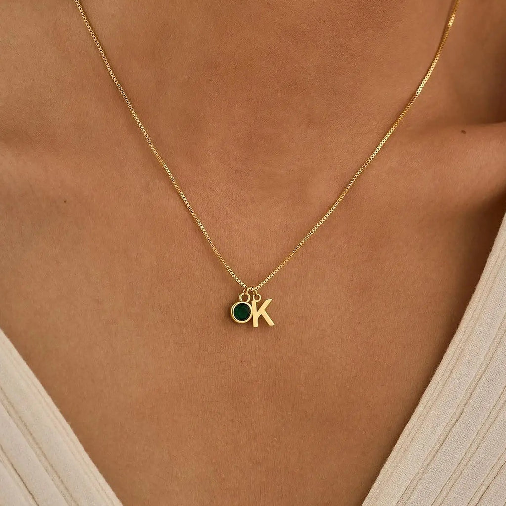 Colar com inicial K e pedra verde ao pescoço