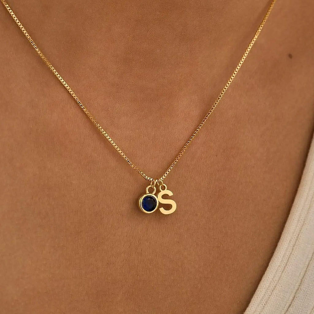 Colar com inicial S e pedra azul ao pescoço