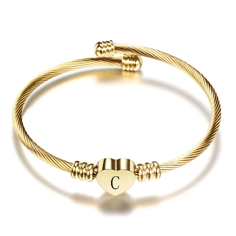 Pulsera rígida dorada con la inicial C en el corazón