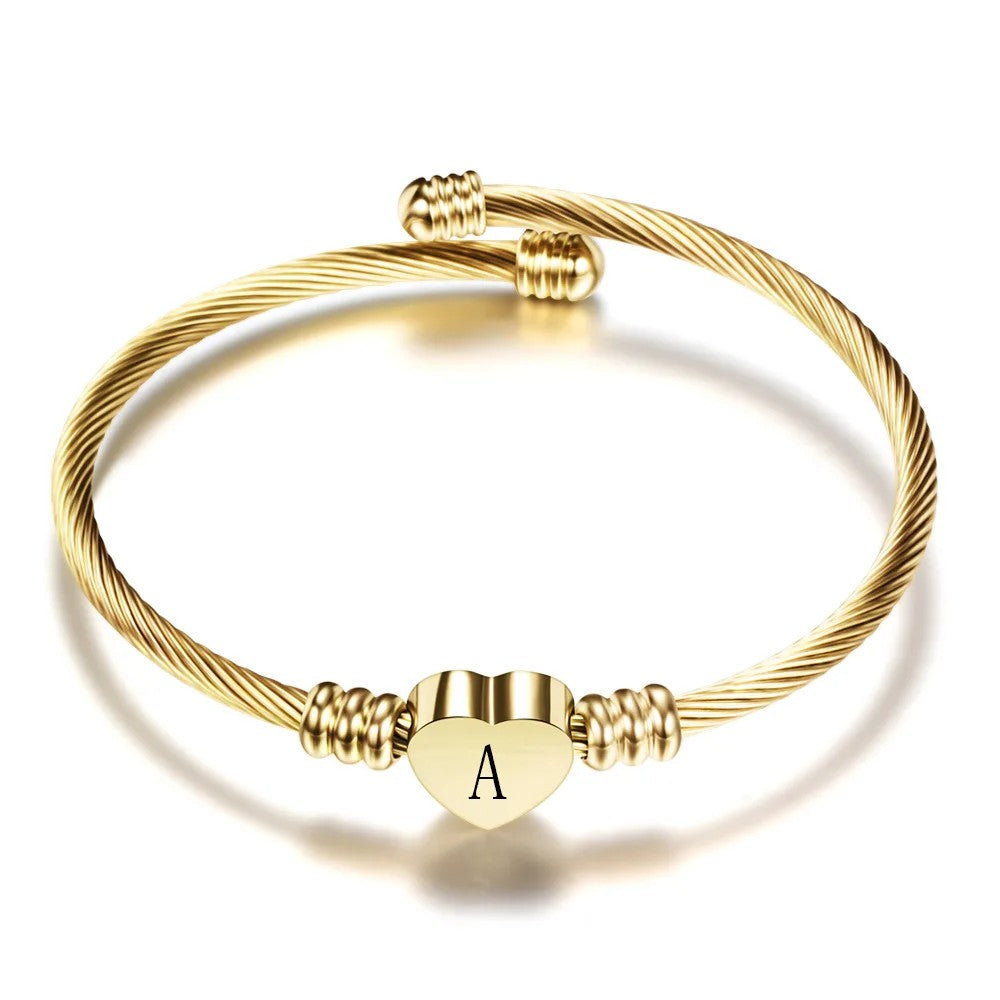 Pulsera rígida dorada de cable trenzado con un corazón y la inicial A